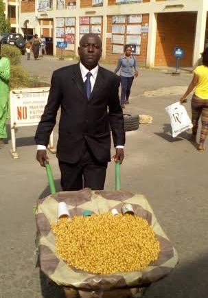 Photos:- Meet The Nigerian Man Who Wears Suit To Hawk Fruit With A Wheelbarrow